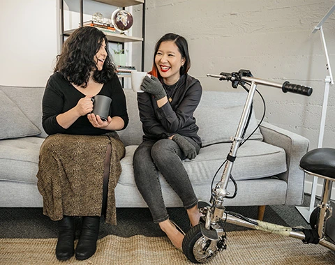 Two women engaged in a friendly discussion on a couch, highlighting support  coordination