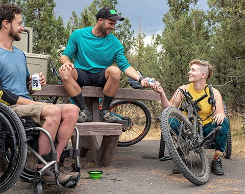 Three men are in a park, One of them is in a wheelchair and they are enjoying the day option